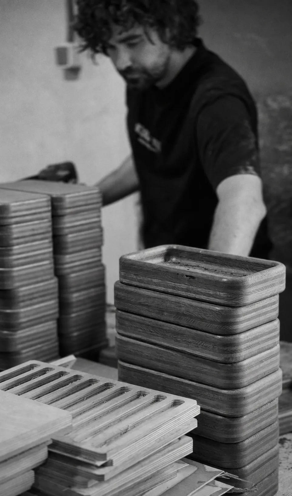 A carpenter by stacks of wooden pieces